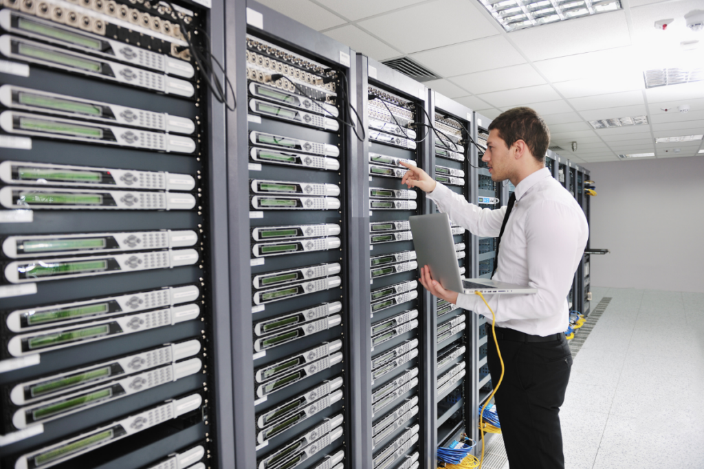 IT engineer working with a laptop beside rows of rack-mounted servers