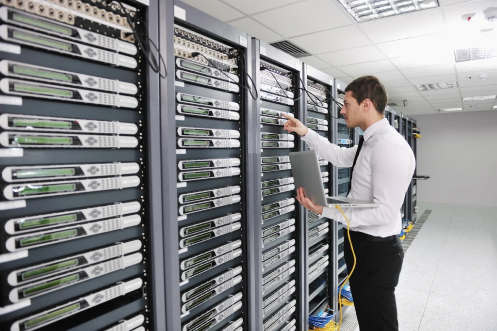 IT engineer working with a laptop beside rows of rack-mounted servers